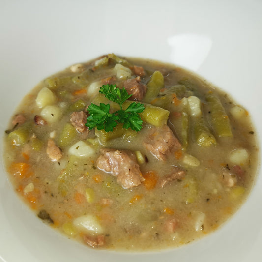 hausgemachter grüne Bohneneintopf angerichtet auf einem Teller garniert mit frischer Petersilie