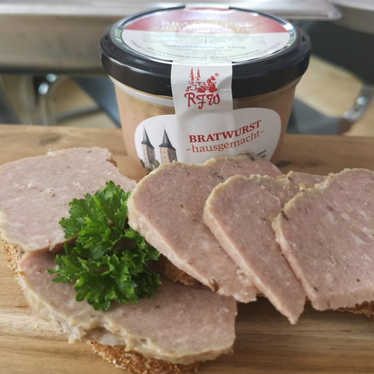 hausgemachte Bratwurst in Scheiben angerichtet auf einer Scheibe Brot garniert mit frischer Petersilie