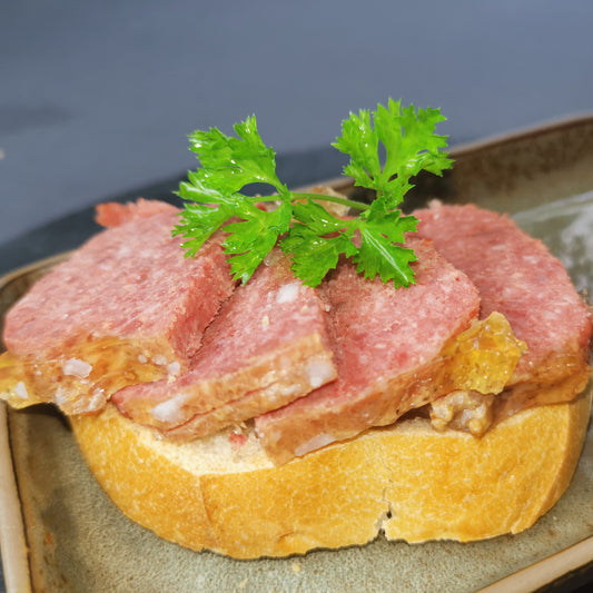 hausgemachtes Frühstücksfleisch Rind in Scheiben geschnitten angerichtet auf einer Scheibe Brot garniert mit frischer Petersilie
