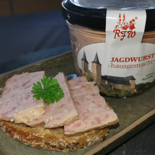 Brotscheibe mit hausgemachter Jagdwurst in scheiben, garniert mit frischer Petersilie, daneben die Glaskonserve