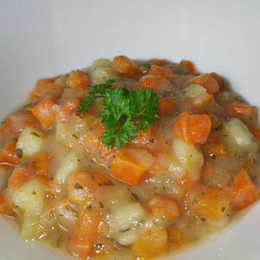 hausgemachter Möhreneintopf auf einem Teller, angerichtet mit frischer Petersilie als Serviervorschlag