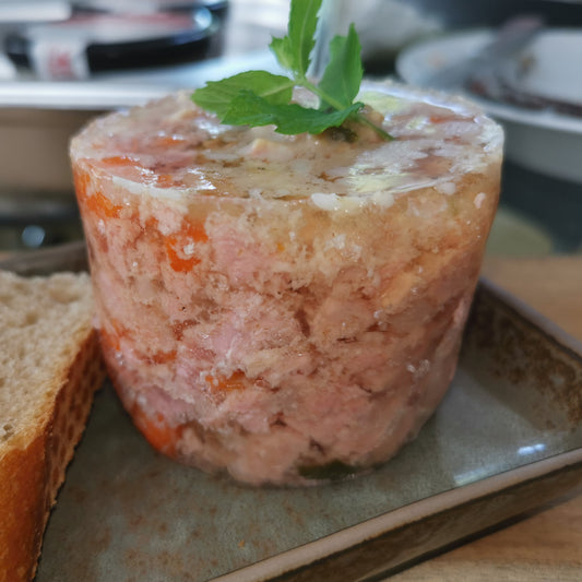 hausgemachte Sülze, garniert mit Petersilie neben einer Brotscheibe